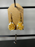 White resin teardrop earrings filled with chunky gold leaf on gold fish hook wires displayed on kraft card
