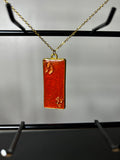 Terracotta and burnt orange resin rectangular bar pendant with gold leaf in gold bezel on a delicate gold chain
