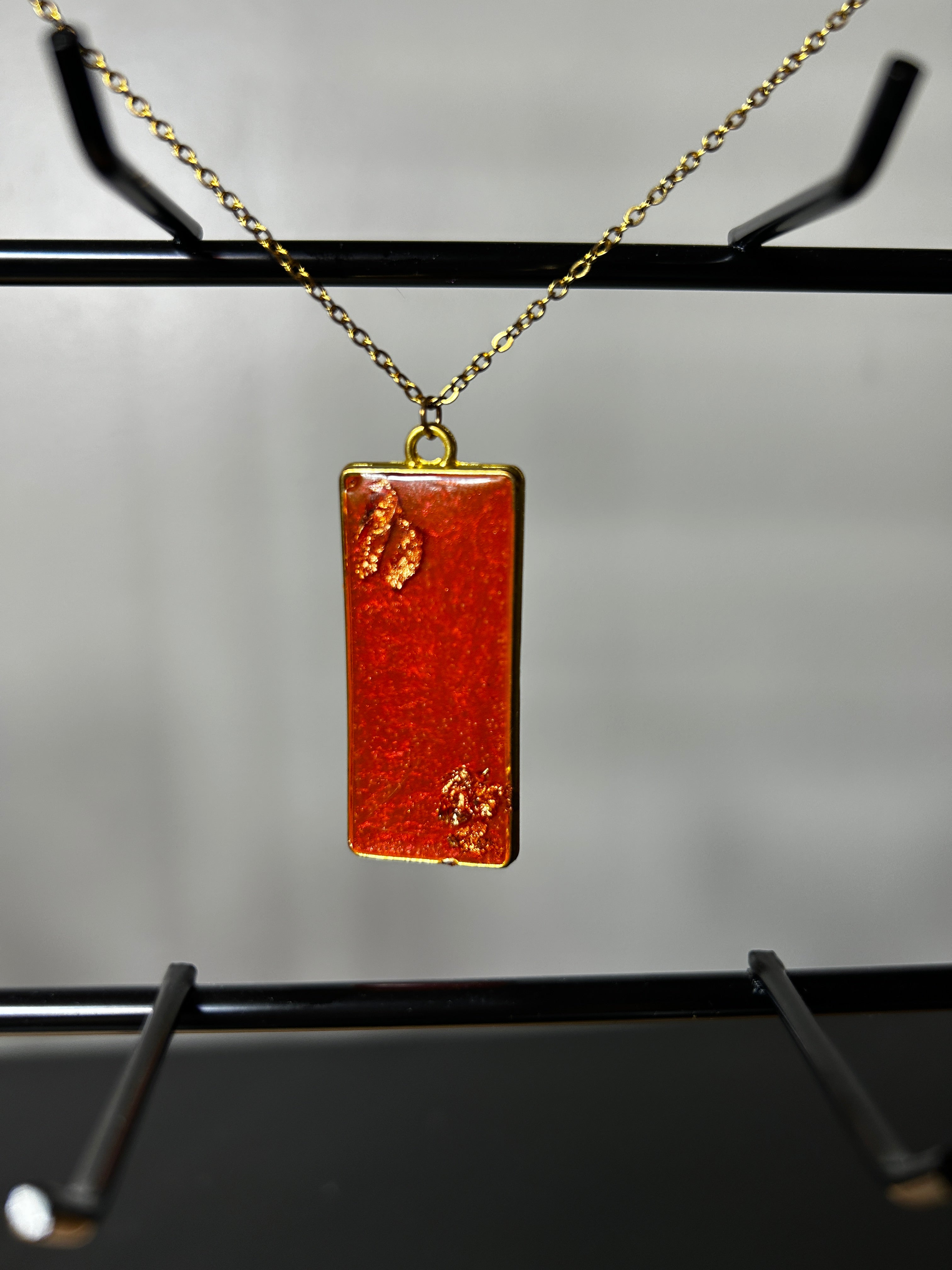 Terracotta and burnt orange resin rectangular bar pendant with gold leaf in gold bezel on a delicate gold chain