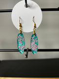 Pink wildflowers in teal resin elongated marquise drop earrings on gold fish hook wires displayed on white circular card