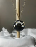 Baby's breath pressed flowers in black resin freeform disc pendant with gold textured edge on delicate gold chain