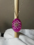 Queen Anne's lace flower in vibrant fuchsia resin oval pendant with gold bezel on gold chain