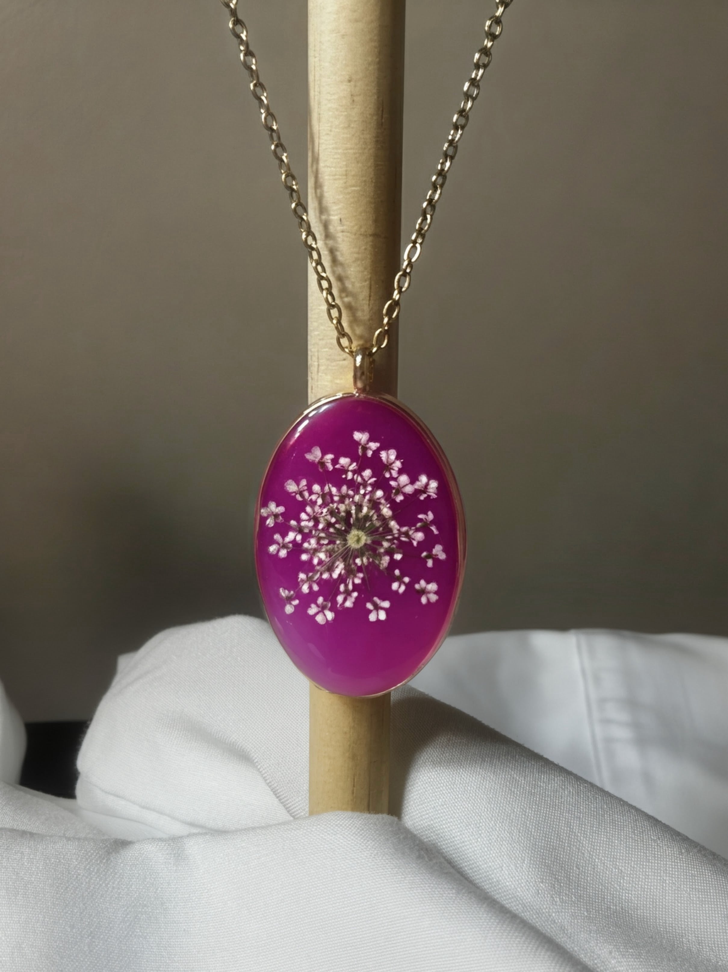 Queen Anne's lace flower in vibrant fuchsia resin oval pendant with gold bezel on gold chain