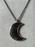 Black resin crescent moon pendant with multicolored galaxy glitter in rose gold bezel on black chain