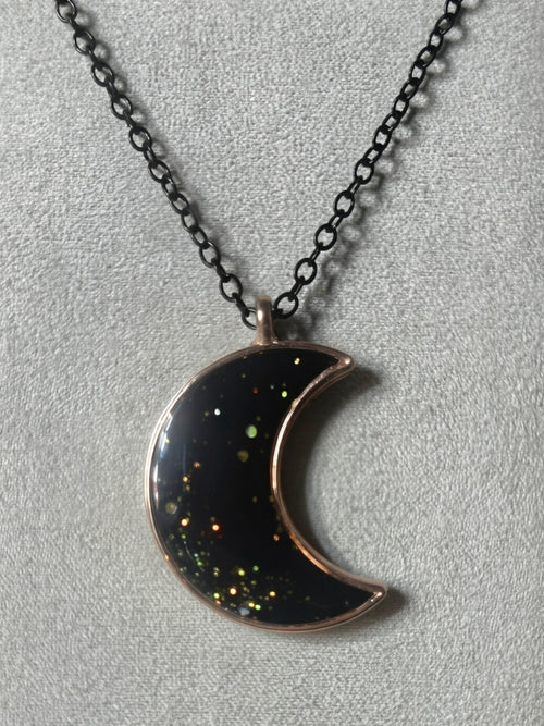 Black resin crescent moon pendant with multicolored galaxy glitter in rose gold bezel on black chain
